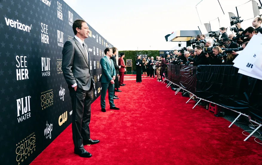 A candid backstage moment at the Critics Choice Awards with a nominee speaking to press in a step-and-repeat interview area