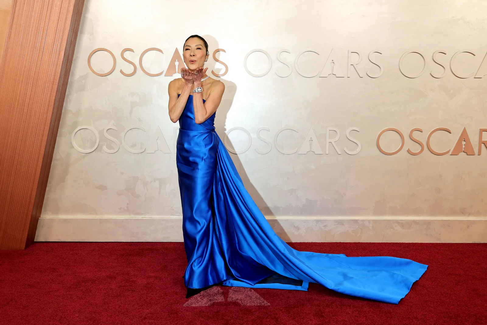 A celebrity on an awards show red carpet with softly contoured cheeks and a satin highlight as photographers take pictures