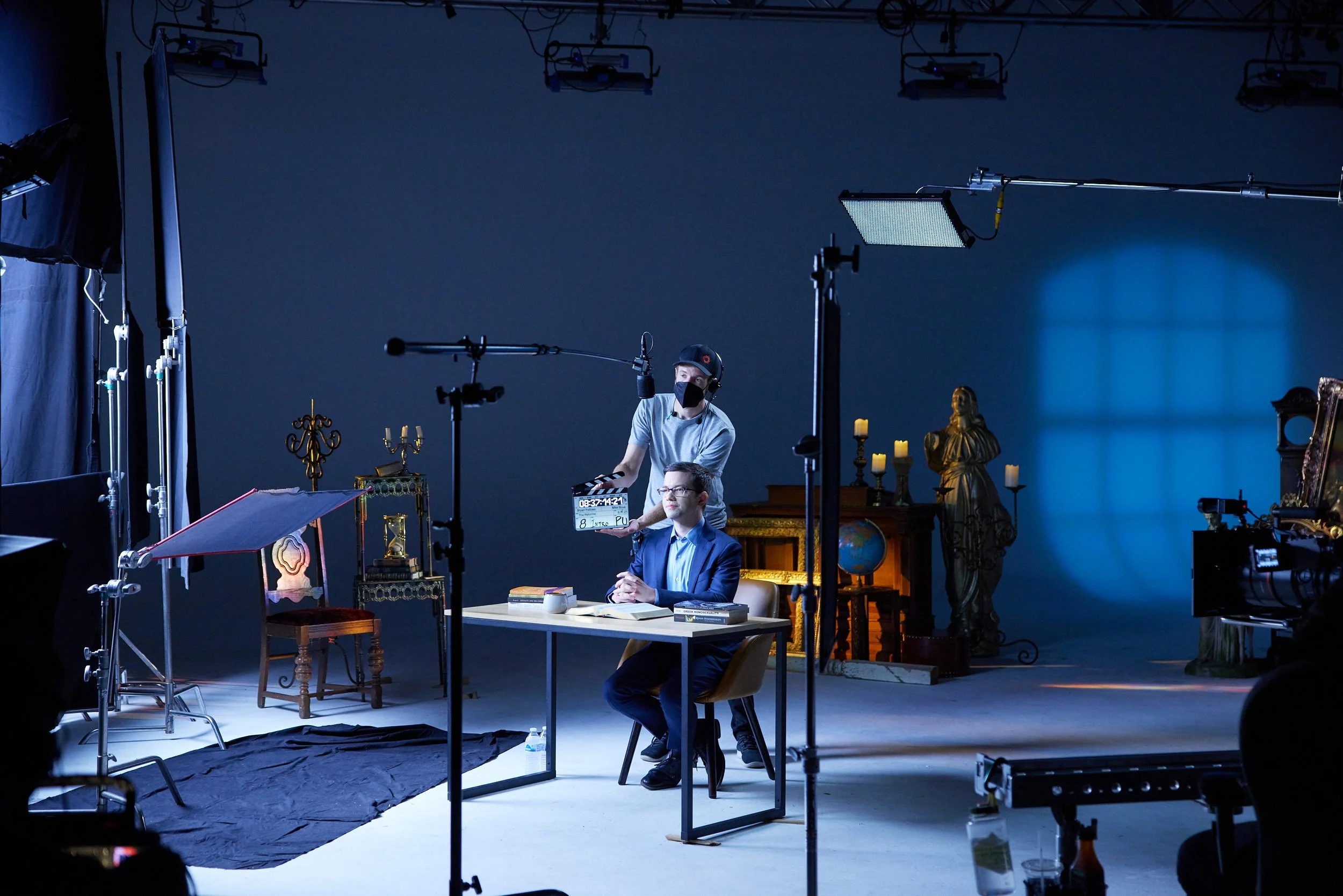 A cinematic studio set with a director chair, camera on a tripod, and soft lighting arranged for a filmed lesson