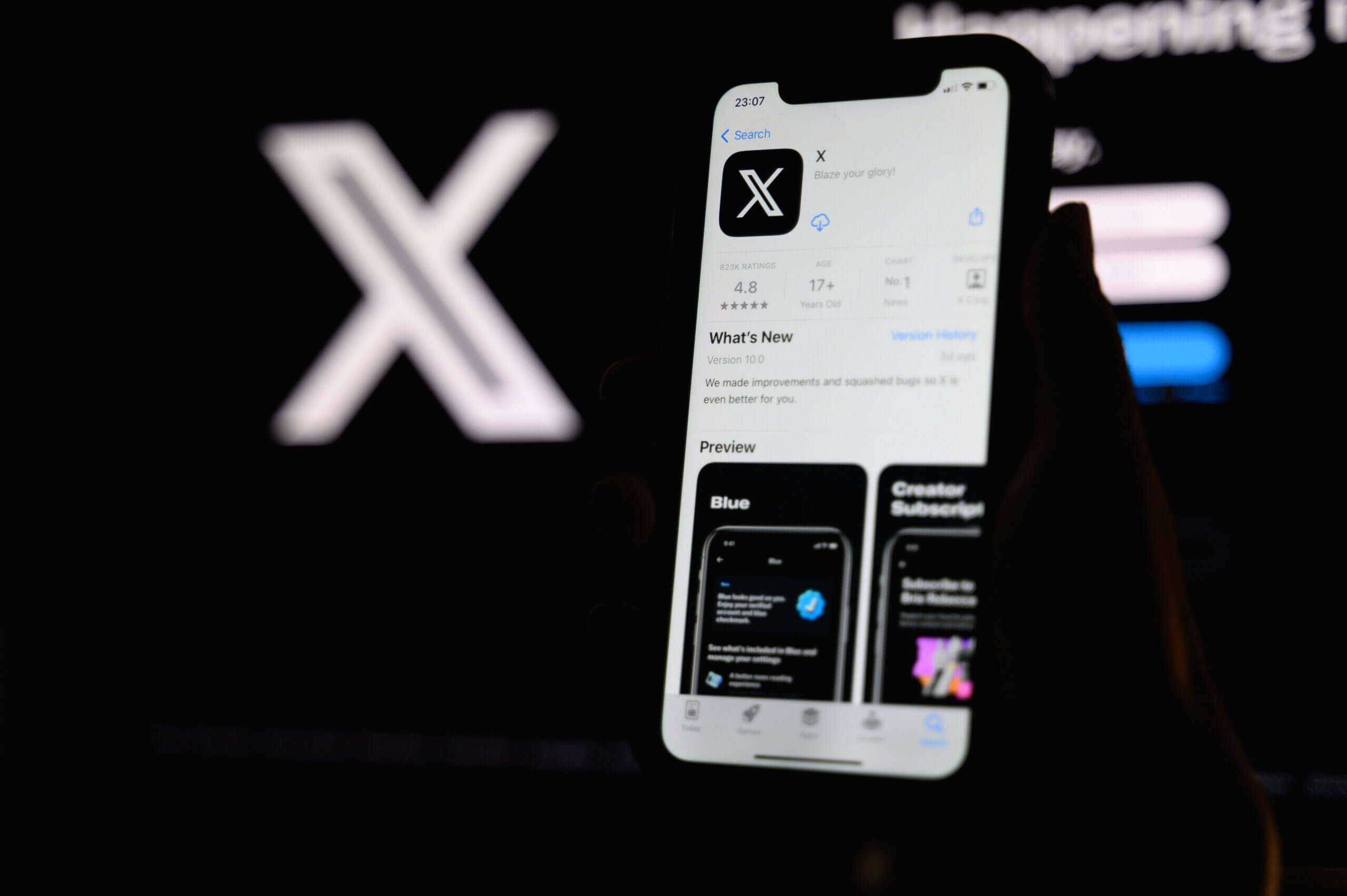 A close-up of a smartphone showing the X app open to a fast-moving hashtag feed