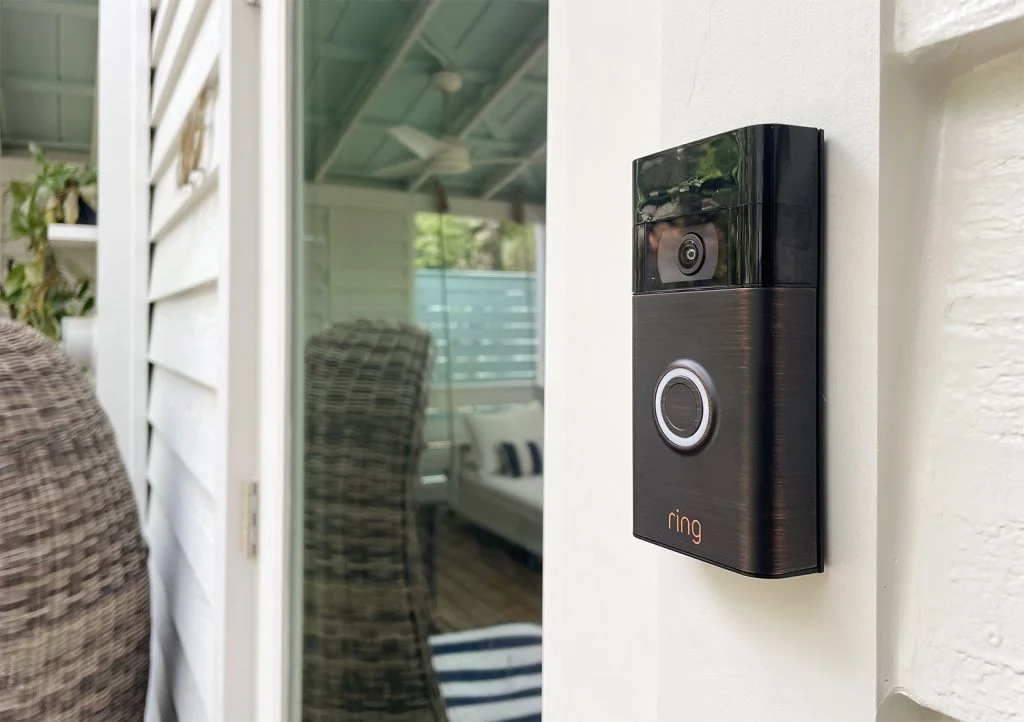 A close view of a video doorbell mounted beside a front door on a well-lit porch