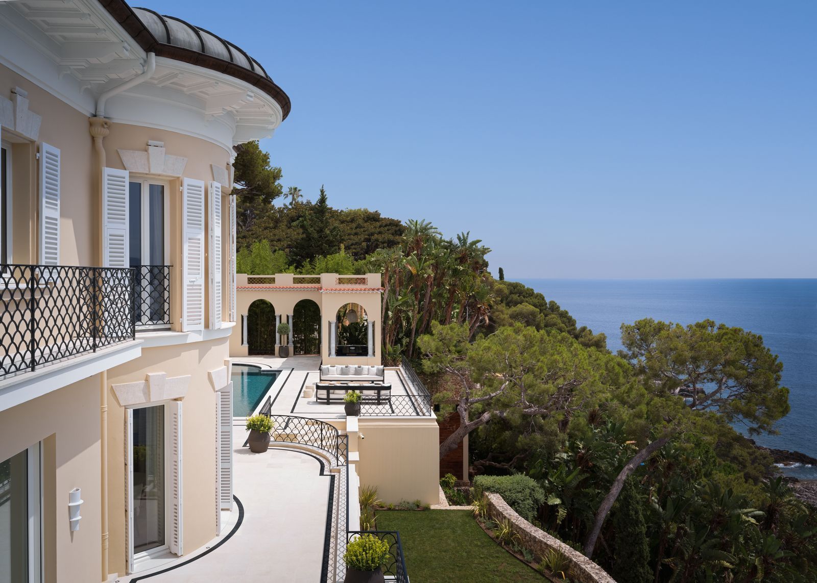 A hillside villa on the French Riviera with a stone terrace and panoramic sea views overlooking a bright blue coastline