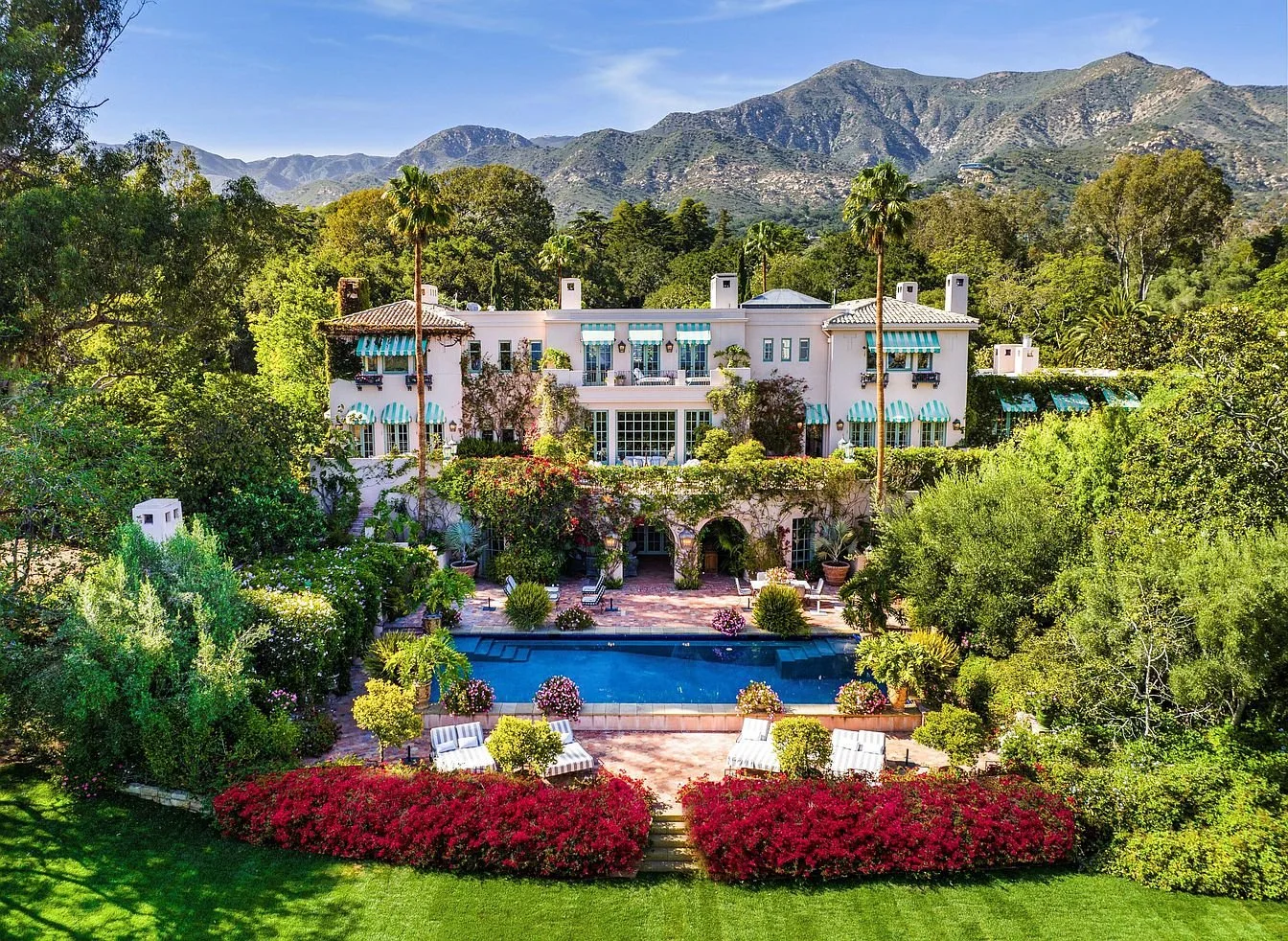 A large Montecito estate with a lush garden, tall palm trees, and a sunlit terrace overlooking manicured grounds
