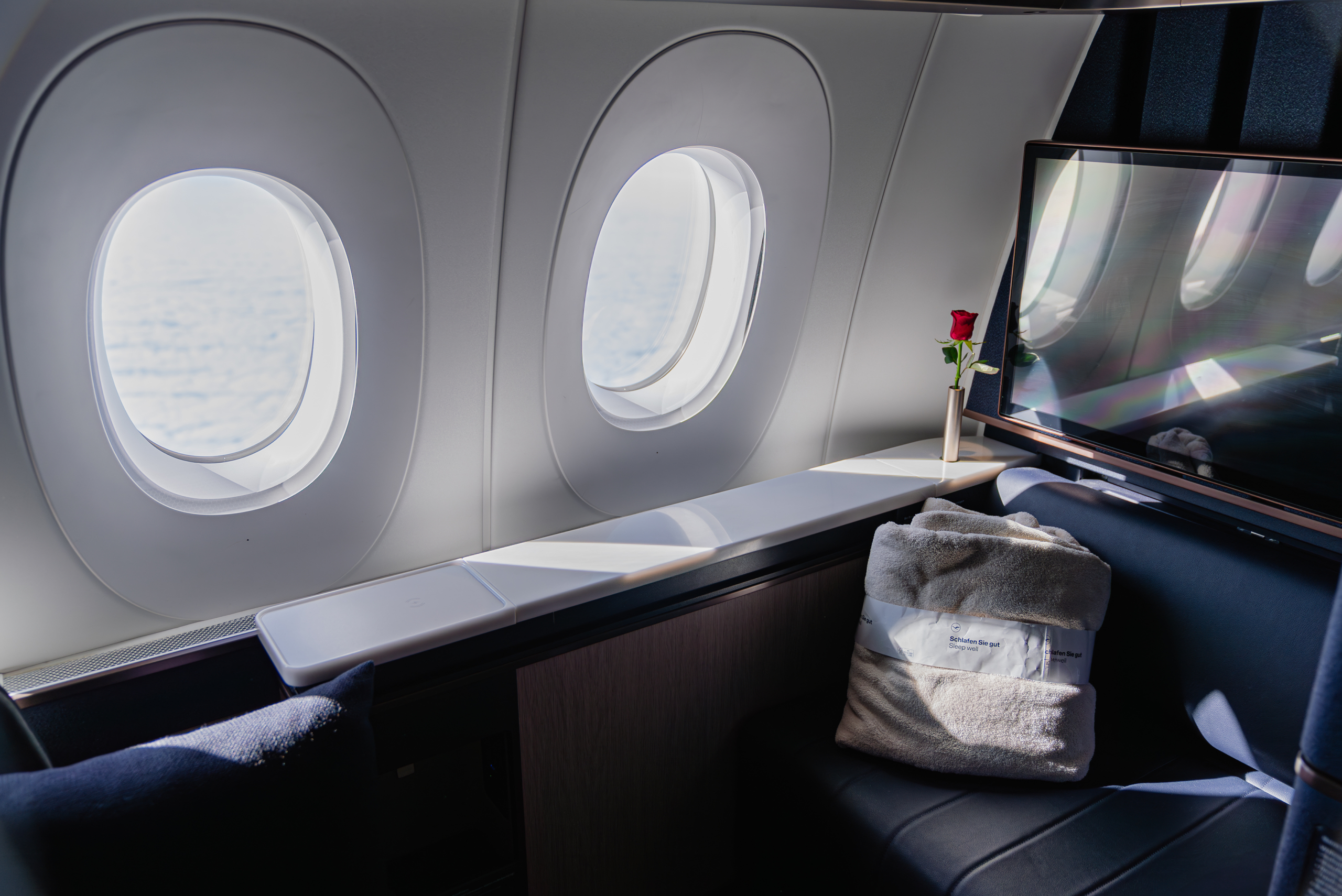 A passenger aircraft cabin window viewed from inside the cabin, showing the window frame and surrounding panel