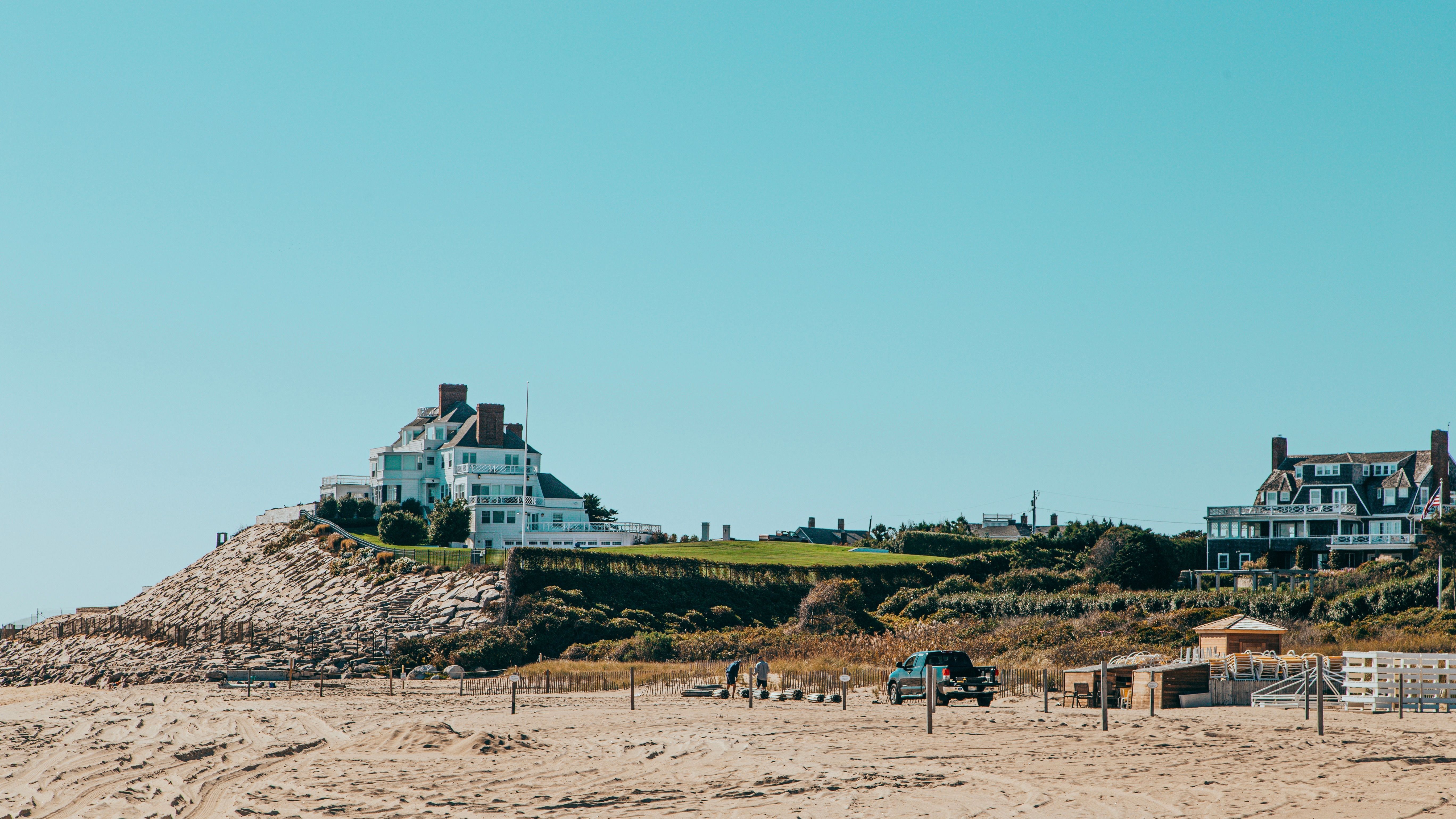 A private coastal residence with tall greenery, a long driveway, and distant ocean views, reflecting a quiet, high-privacy enclave