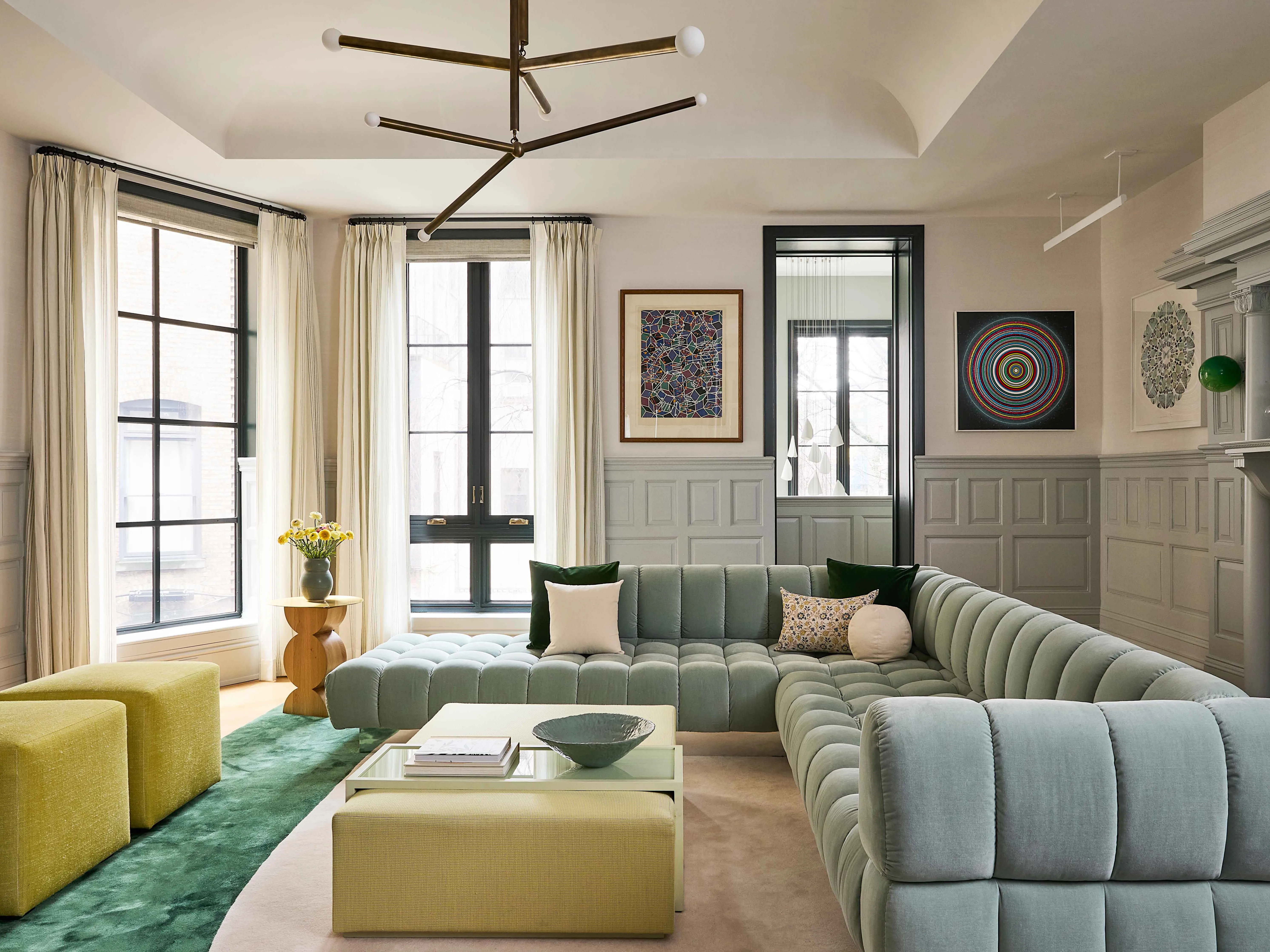 A stylish living room with a neutral sofa, a round coffee table, layered rugs, and warm lighting, arranged like a polished celebrity home tour