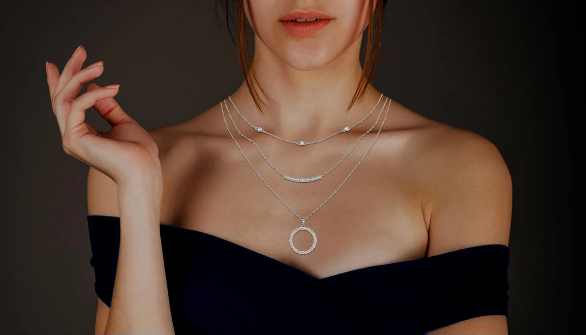 A stylist fastens a diamond necklace at an actress’s neck while she wears a gown in a dressing room.