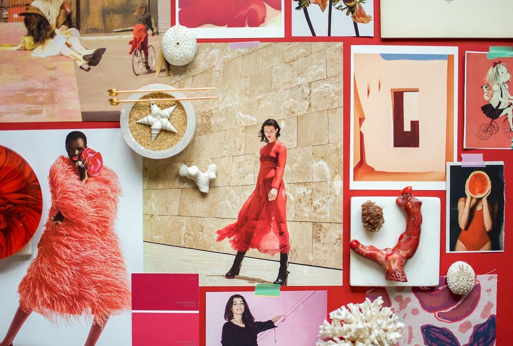 A stylist’s desk with printed runway photos, fabric swatches, lipstick samples, and a notebook filled with look notes.