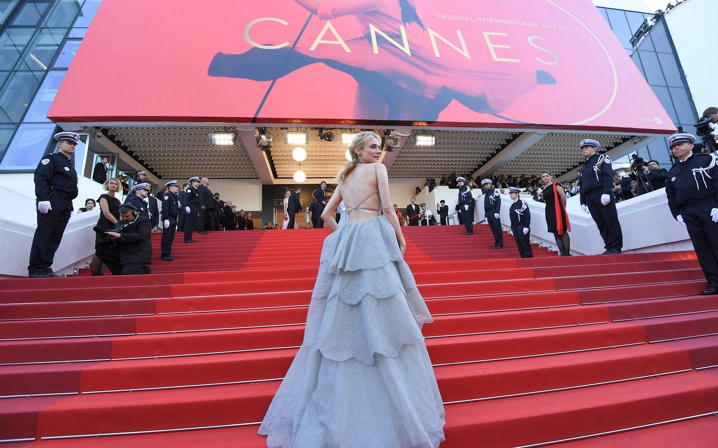 Celebrities arriving at a major film festival premiere at night, walking up steps toward a theater entrance with photographers nearby