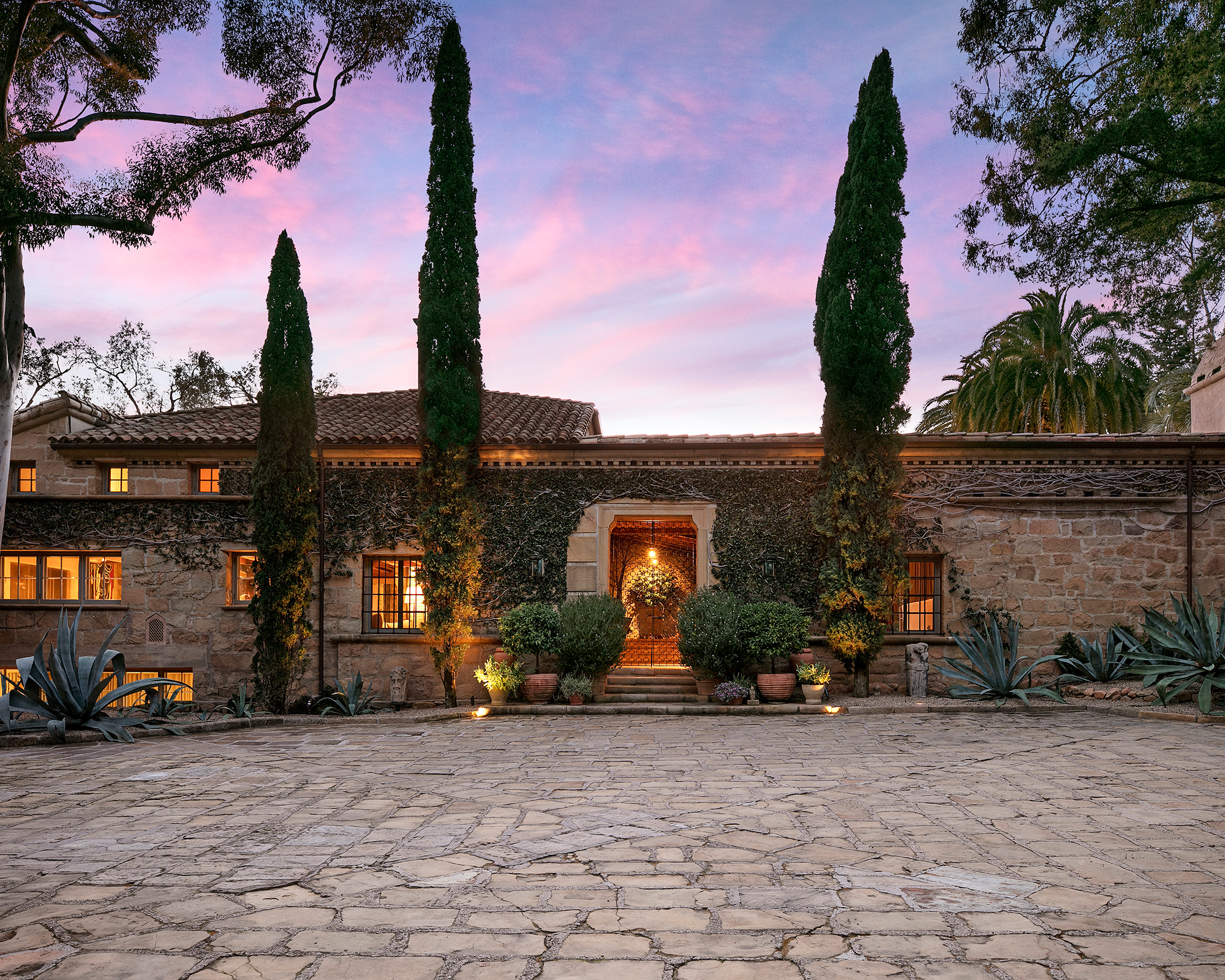 Ellen DeGeneres outdoors near a bright, landscaped California home with mature trees and a clean, modern farmhouse exterior