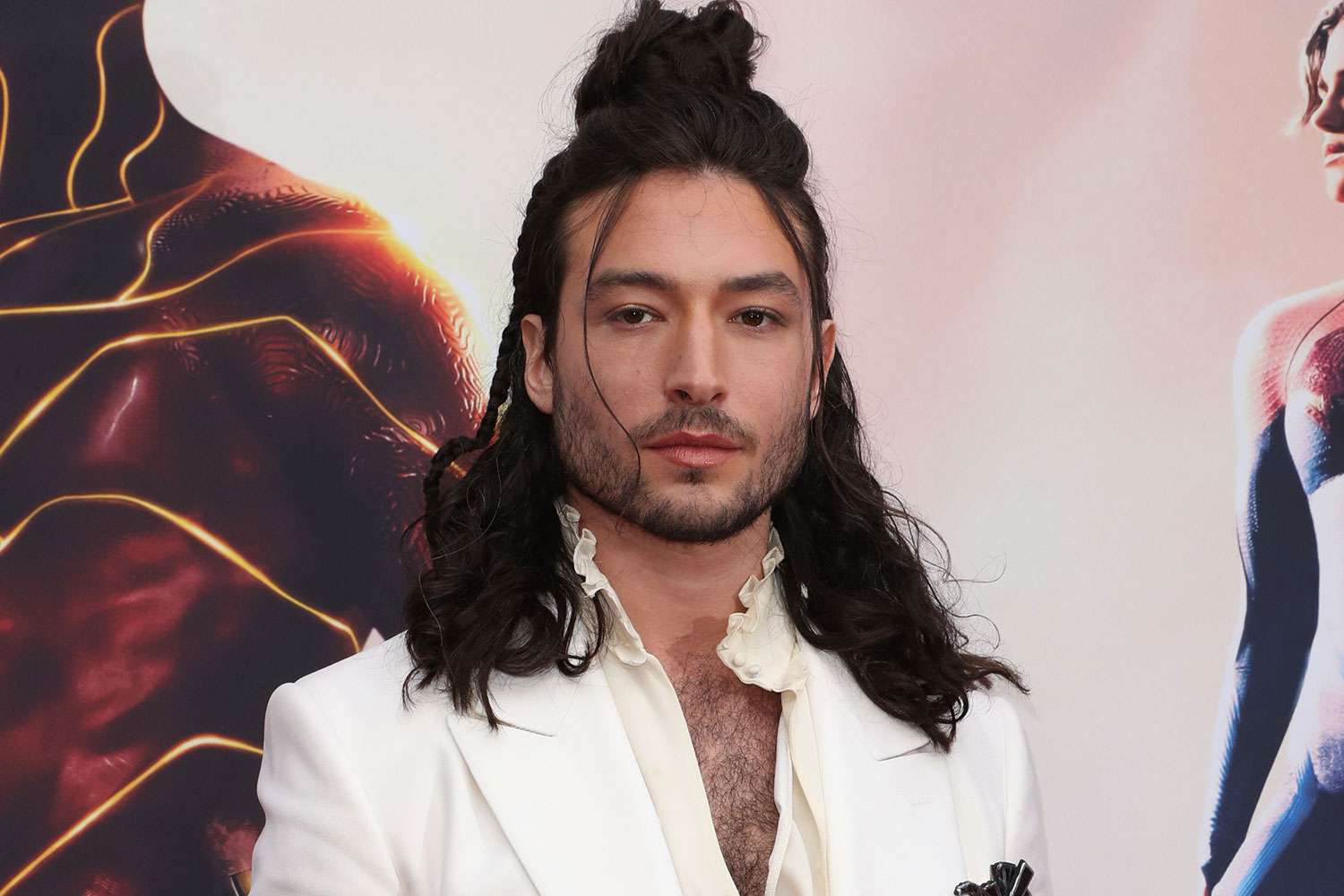 Ezra Miller posing on a red carpet in formal fashion at an entertainment event with a step-and-repeat backdrop