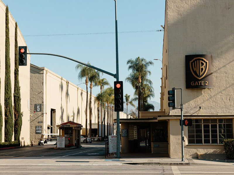 Fans standing in a standby line outside a television studio in Los Angeles in the late afternoon, dressed casually and holding small bags