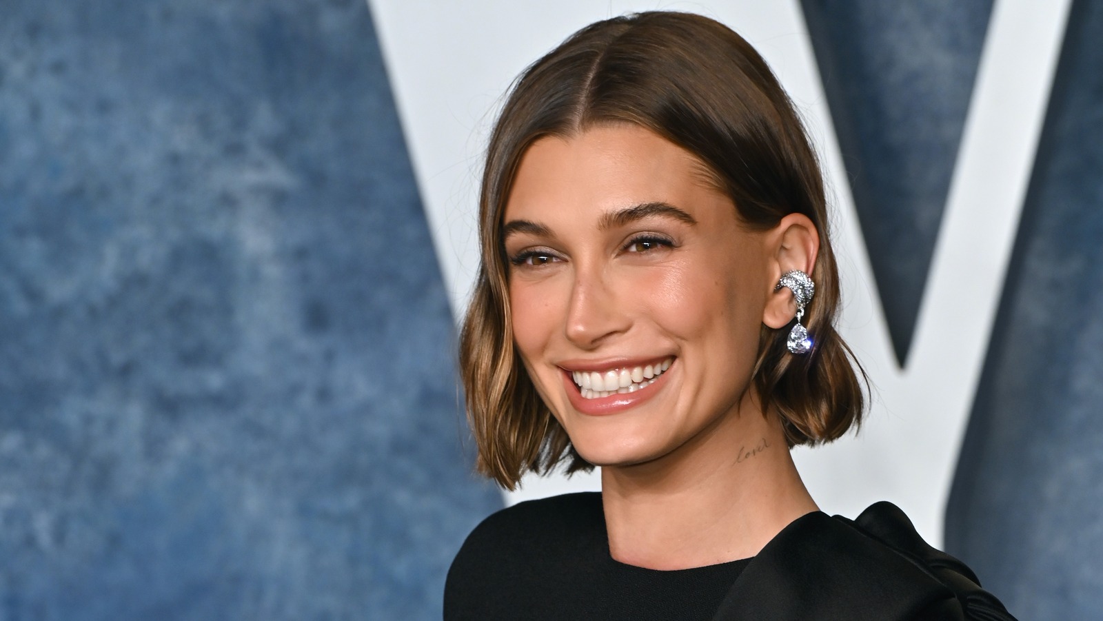 Hailey Bieber wearing a minimalist outfit with her shorter bob styled smooth and tucked to emphasize the jawline.