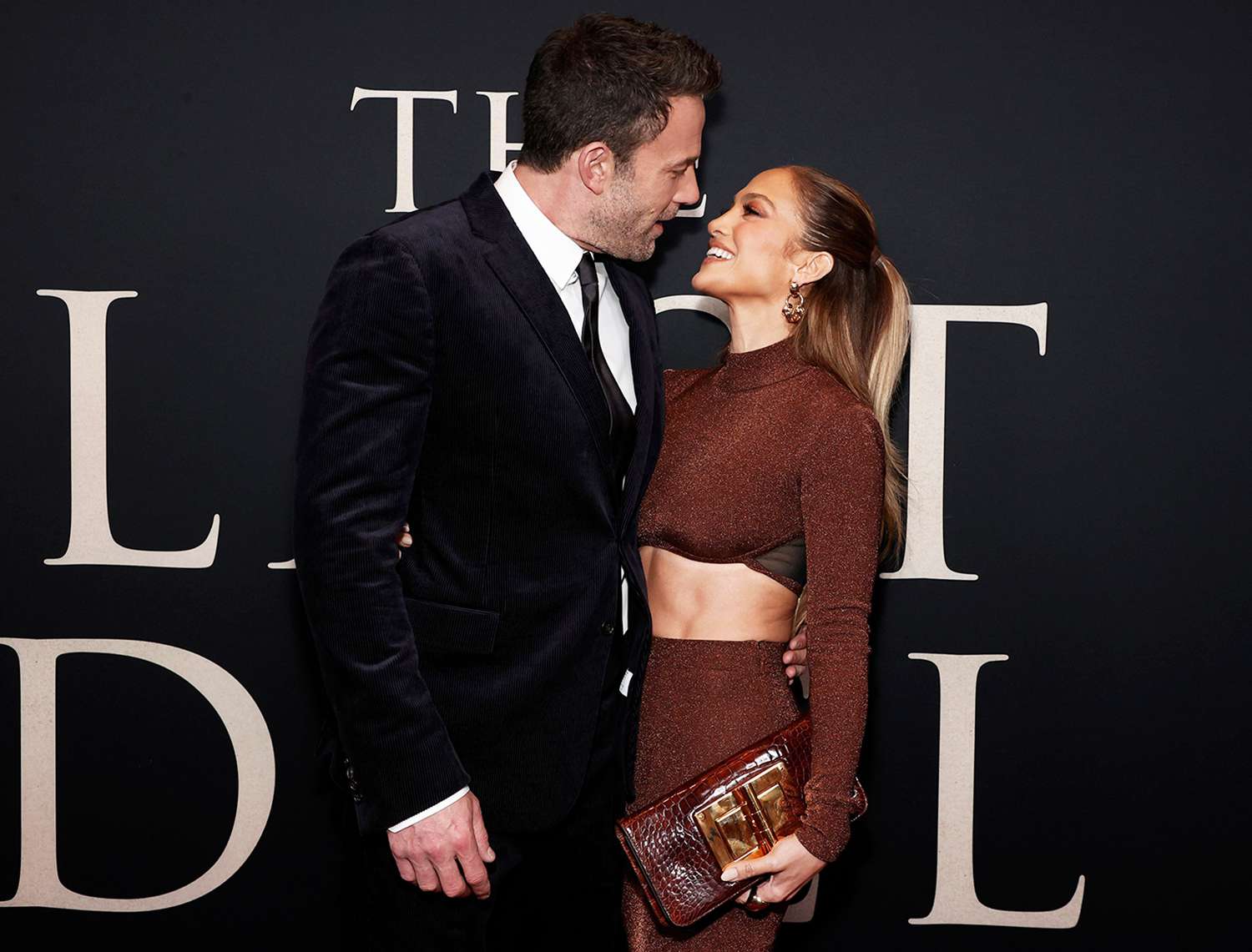 Jennifer Lopez and Ben Affleck posing together at a formal premiere-style event while photographers capture images
