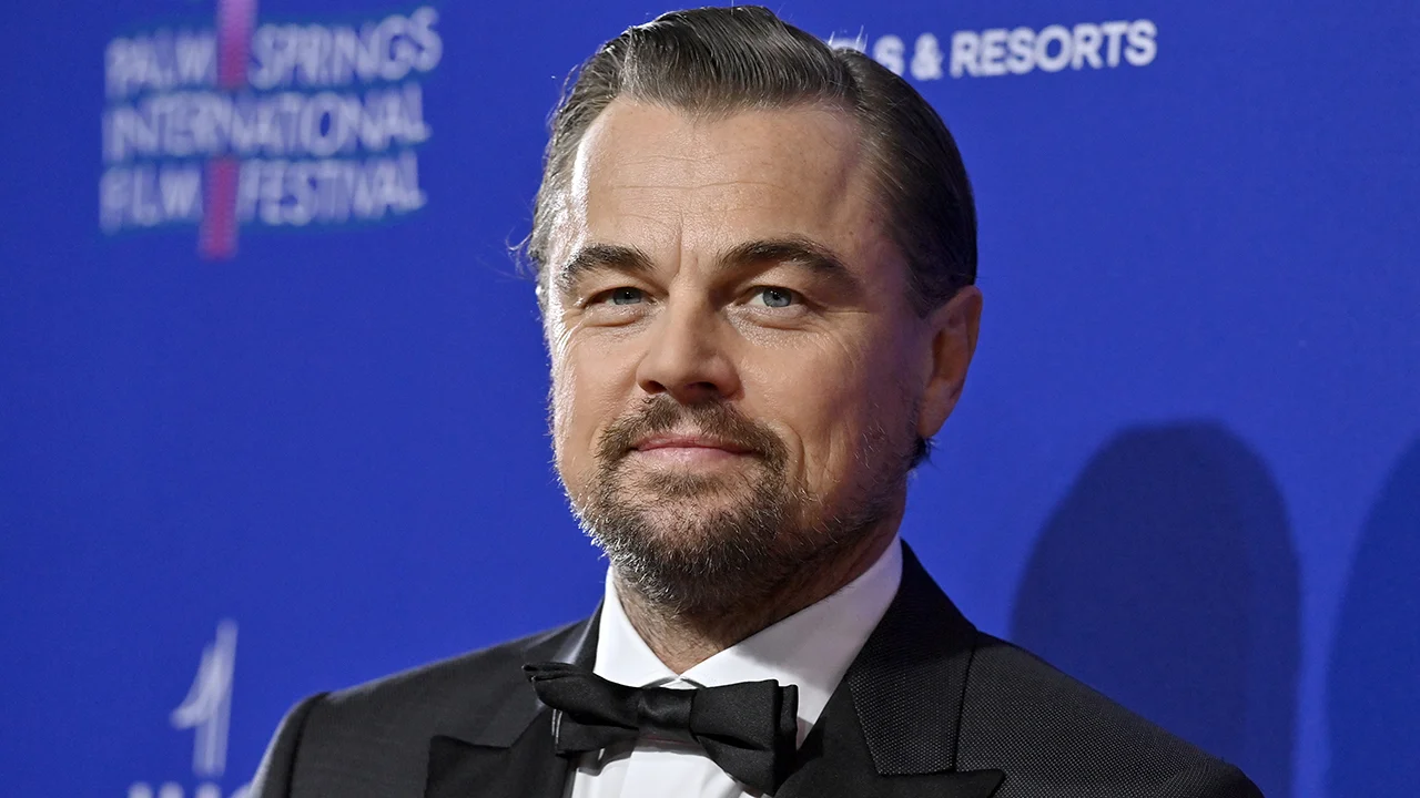 Leonardo DiCaprio posing for photographers at a film premiere, wearing a tailored suit and a composed expression