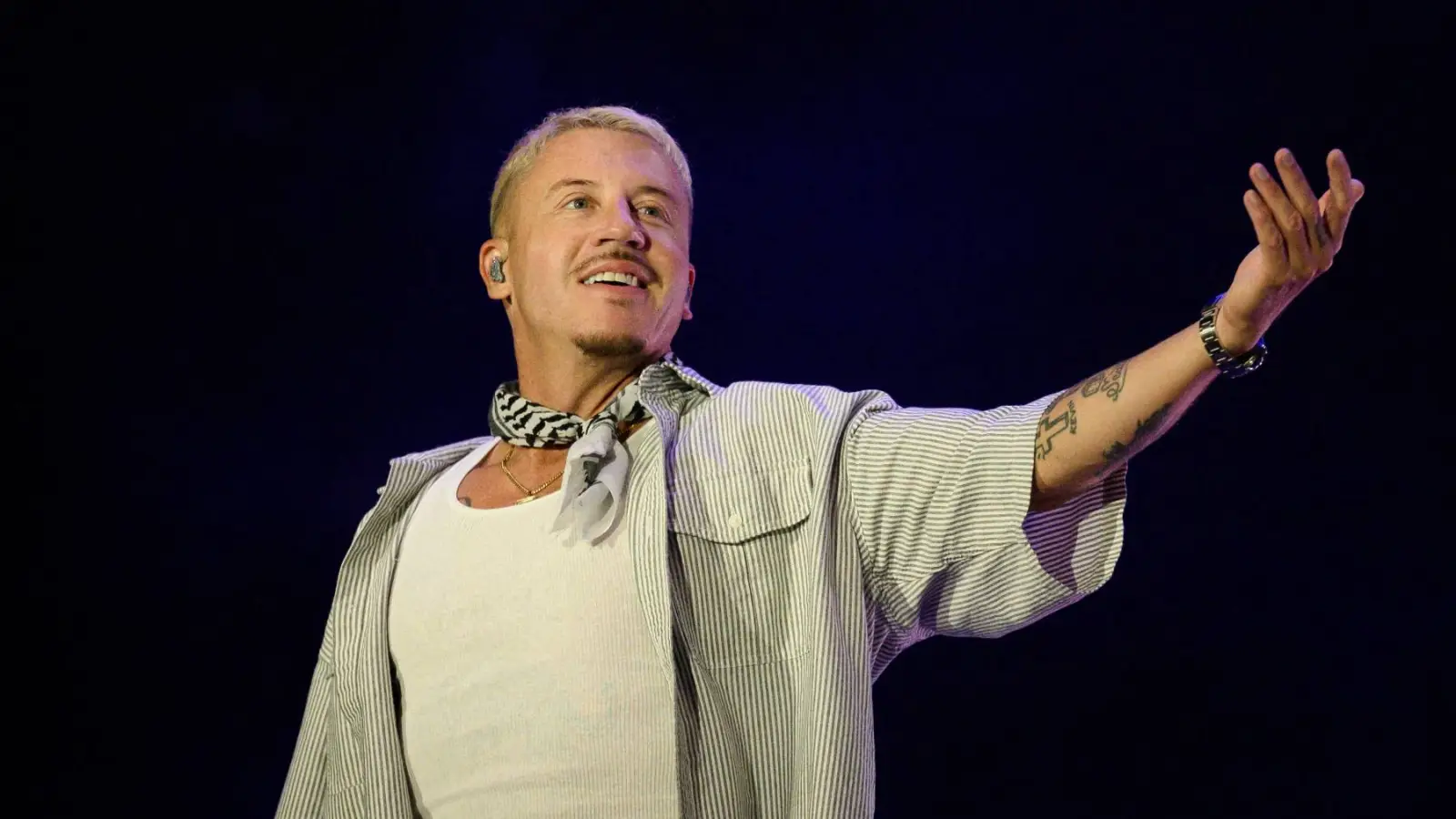 Macklemore performing live onstage with a microphone during a concert