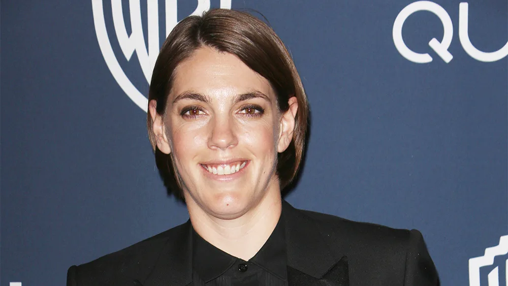 Megan Ellison attending an awards event in an evening outfit, standing near a theater entrance with bright flash photography