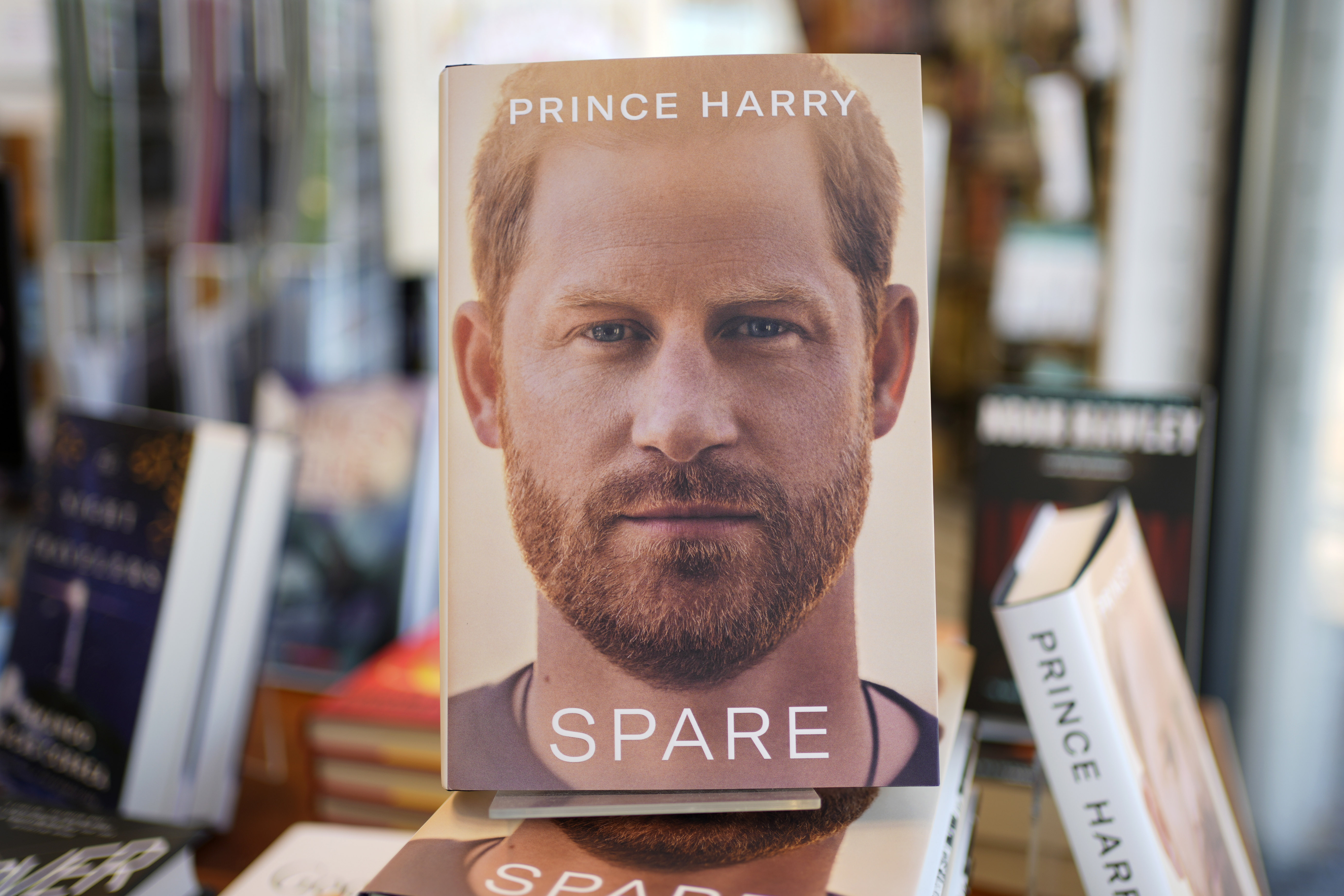 Prince Harry photographed at a public event, wearing a suit, captured in a serious candid moment