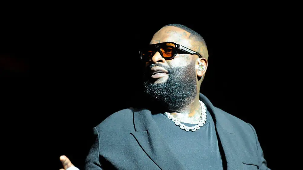 Rick Ross arriving at a public event, surrounded by attendees and cameras, photographed in a candid moment