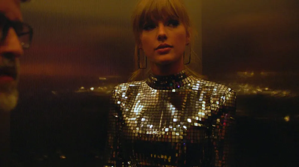 Taylor Swift seated at a piano in a softly lit room, mid-songwriting moment, focused on the keys