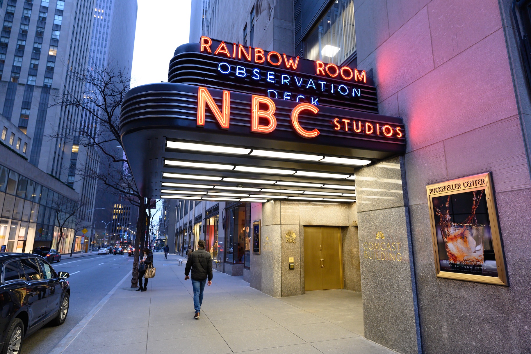 The exterior of NBC Studios at Rockefeller Center in New York City with pedestrians walking by in the afternoon