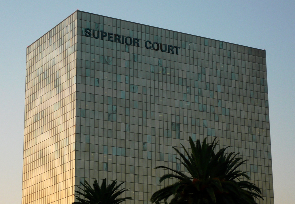 The exterior of a downtown Los Angeles courthouse with people entering through glass doors in daytime