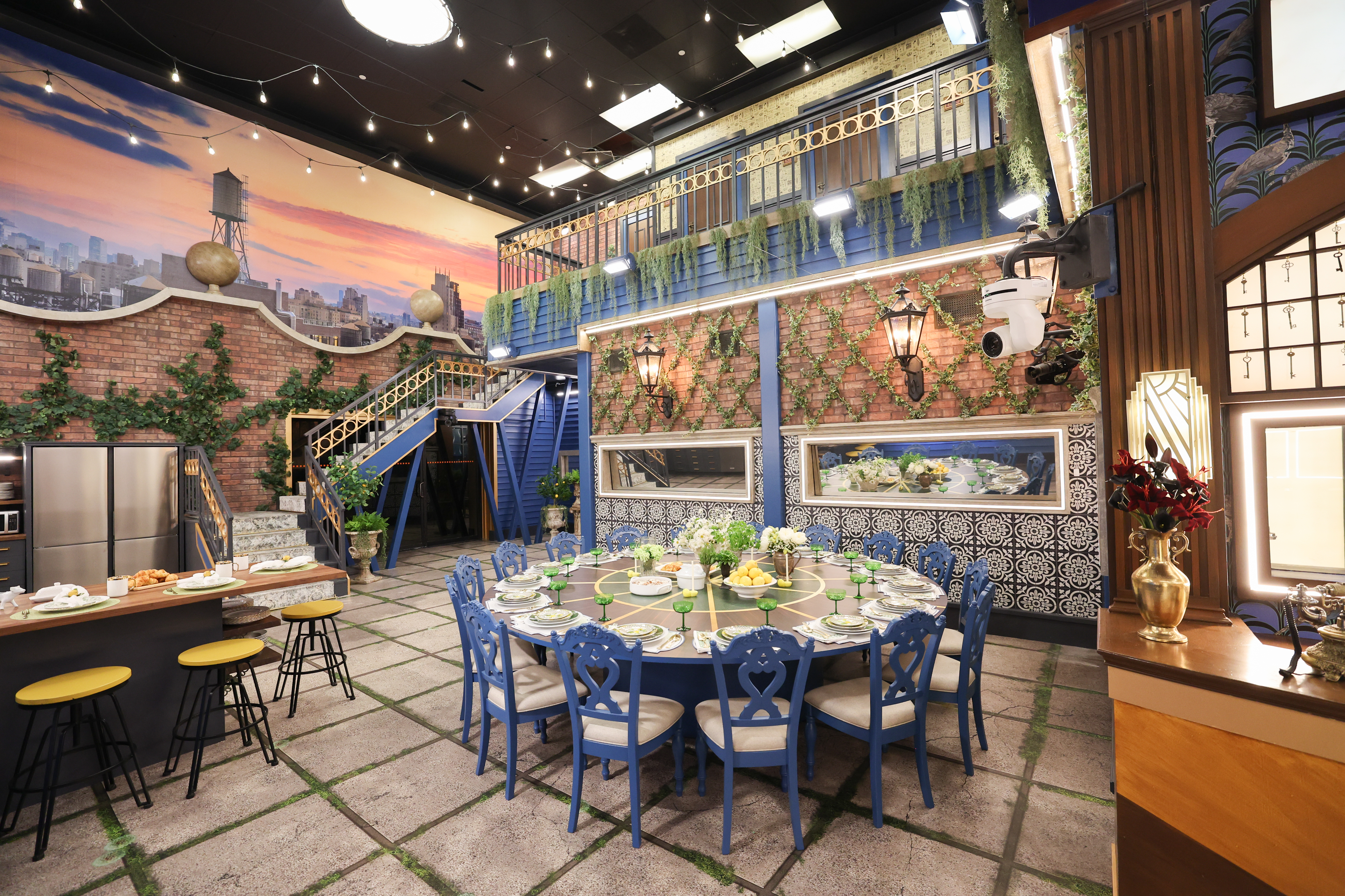 The exterior of the Big Brother house set at night with lit windows and visible production lighting